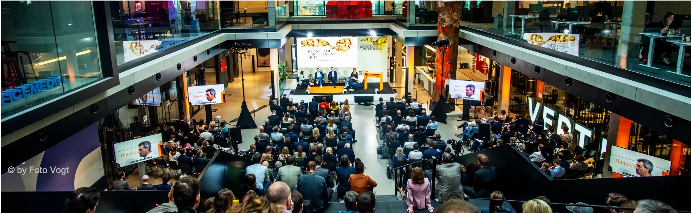 Blick von oben ins volle Atrium beim Handelsblatt KI Summit 2025, vorne das Panel